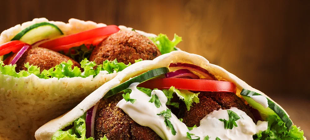 Falafel and fresh vegetables in pita bread on wooden table