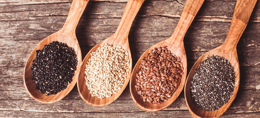 Chia and flax seeds, white and black sesame in wooden spoons